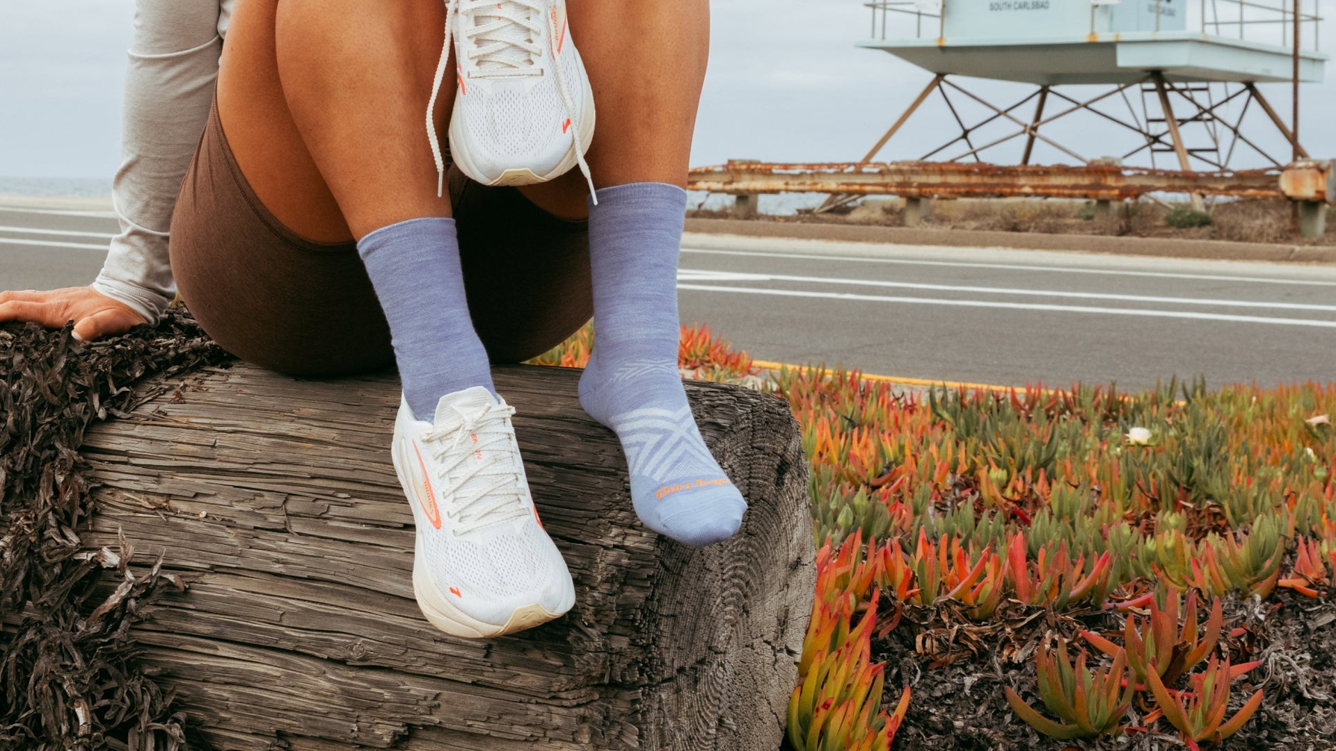 Women sitting on log wearing a sneaker and micro crew running sock in lavender
